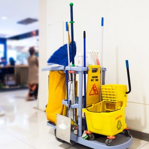 Cleaning cart with brooms, mops, and janitorial supplies